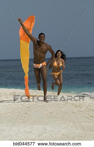 Stock Photo - Hispanic couple flying kite at beach. Fotosearch