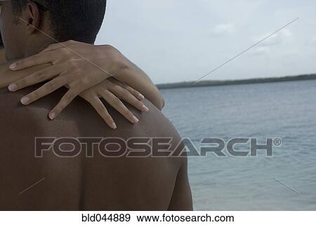 Stock Photo - Hispanic couple hugging at beach. Fotosearch