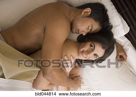 Picture - Hispanic couple hugging in bed. Fotosearch