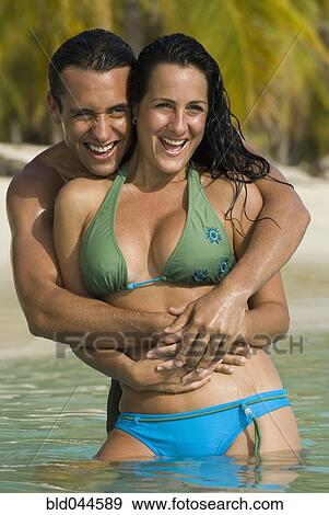Stock Photo - Hispanic couple hugging in water. Fotosearch