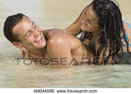 Stock Image - Hispanic couple playing in water. Fotosearch