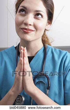 Stock Image - Hispanic female medical professional praying. Fotosearch