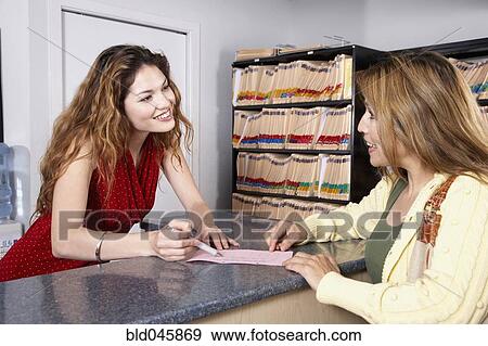 Stock Photo - Hispanic female medical professional helping patient. Fotosearch