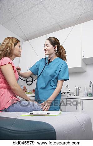 Stock Photo - Hispanic female medical professional examining patient. Fotosearch