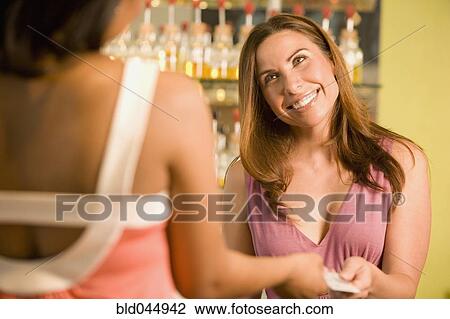 Stock Image - Hispanic female sales clerk taking credit card. Fotosearch