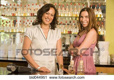 Stock Image - Hispanic female sales clerks at perfume store. Fotosearch