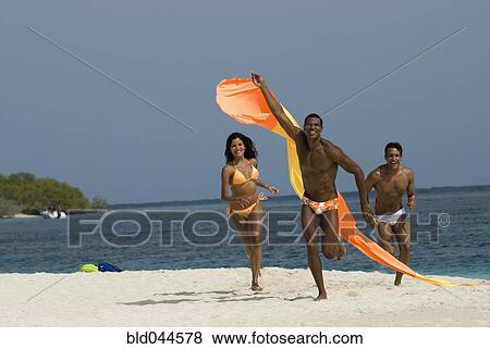 Stock Photo - Hispanic friends flying kite at beach. Fotosearch