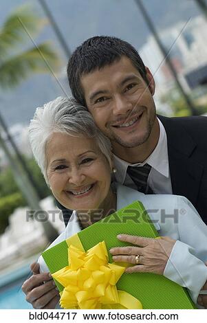 Stock Photo - Hispanic man giving gift to mother. Fotosearch