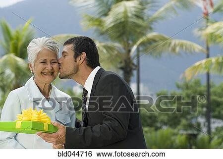 Hispanic man giving gift to mother View Large Photo Image Stock Photograph - Hispanic man giving gift to mother. Fotosearch