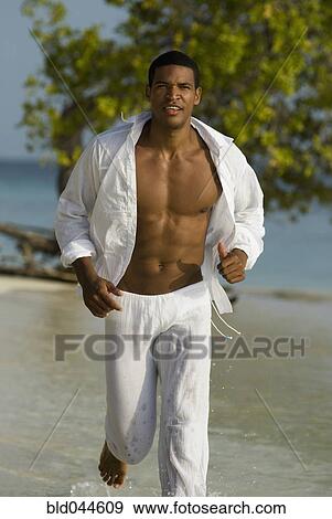 Stock Photo - Hispanic man jogging on beach. Fotosearch