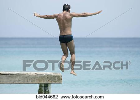Hispanic man jumping off dock View Large Photo Image Stock Image - Hispanic man jumping off dock. Fotosearch
