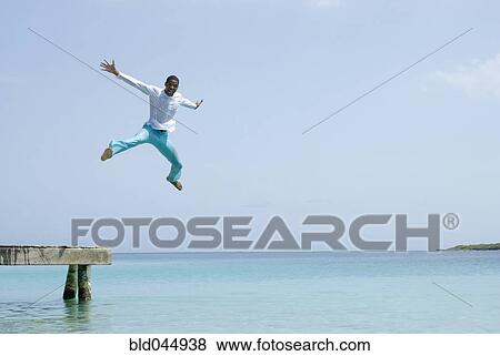 Hispanic man jumping off dock View Large Photo Image Stock Photo - Hispanic man jumping off dock. Fotosearch