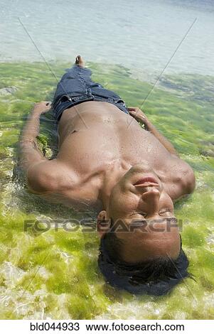 Stock Image - Hispanic man laying in water. Fotosearch