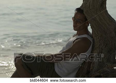 Hispanic man leaning against tree View Large Photo Image Picture - Hispanic man leaning against tree. Fotosearch