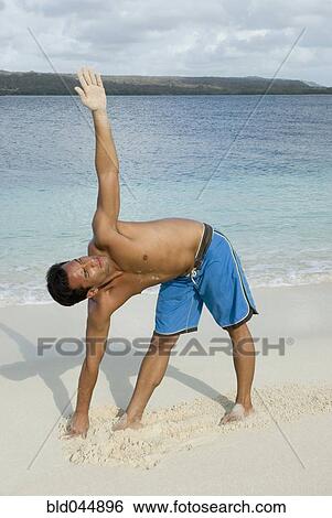 Stock Photograph - Hispanic man practicing yoga at beach. Fotosearch