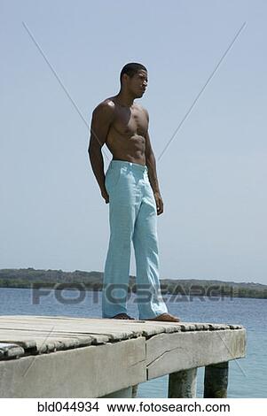Picture - Hispanic man standing on dock. Fotosearch