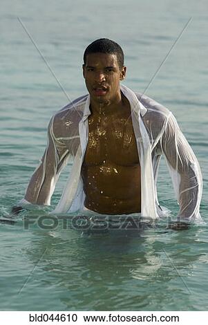 Stock Image - Hispanic man wearing clothing in water. Fotosearch
