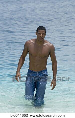 Stock Image - Hispanic man wearing jeans in water. Fotosearch