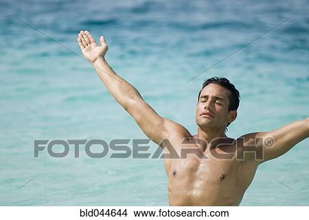 Hispanic man with arms outstretched at beach View Large Photo Image Picture - Hispanic man with arms outstretched at beach. Fotosearch
