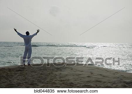 Hispanic man with arms raised at beach View Large Photo Image Stock Photography - Hispanic man with arms raised at beach. Fotosearch