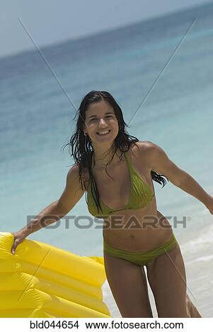 Picture - Hispanic woman holding float at beach. Fotosearch