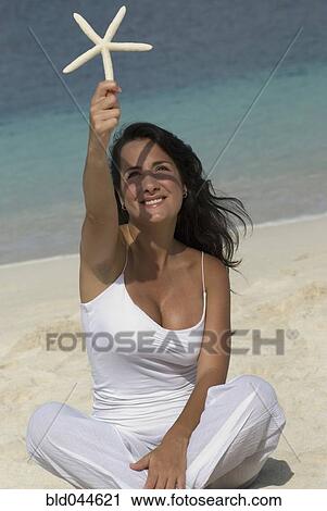 Stock Image - Hispanic woman holding starfish. Fotosearch
