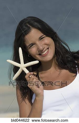 Stock Image - Hispanic woman holding starfish. Fotosearch