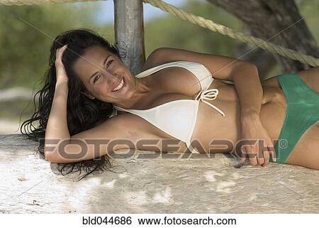Stock Photograph - Hispanic woman laying in sand. Fotosearch