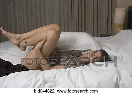 Stock Image - Hispanic woman laying on bed. Fotosearch