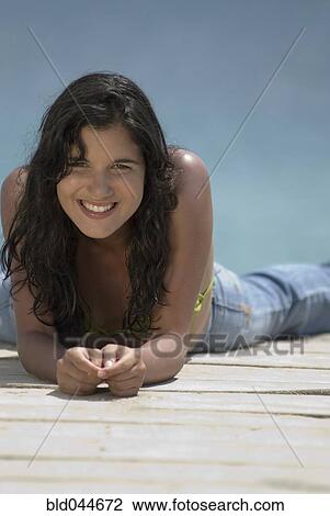 Stock Image - Hispanic woman laying on dock. Fotosearch