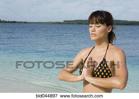 Stock Photo - Hispanic woman practicing yoga at beach. Fotosearch