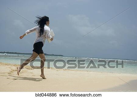 Stock Photograph - Hispanic woman running on beach. Fotosearch