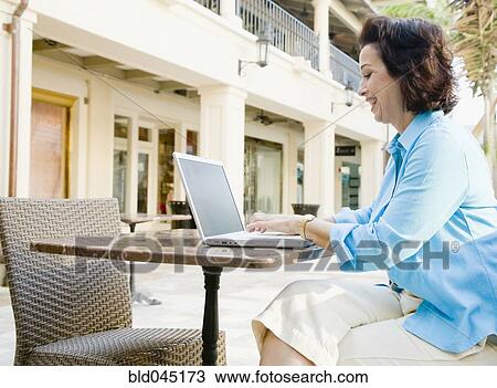 Stock Image - Hispanic woman typing on laptop. Fotosearch