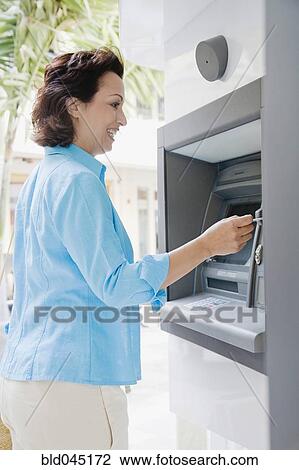 Stock Image - Hispanic woman using automatic teller machine. Fotosearch