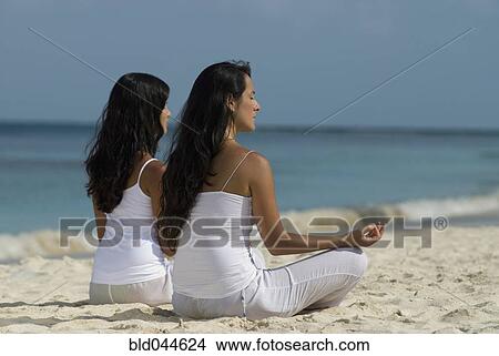 Picture - Hispanic women meditating at beach. Fotosearch