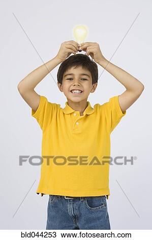 Middle Eastern boy holding light bulb over head View Large Photo Image Stock Image - Middle Eastern boy holding light bulb over head. Fotosearch