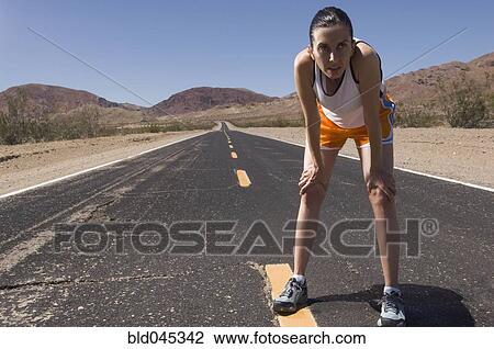 Stock Image - Mixed Race female runner on road. Fotosearch