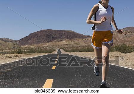 Stock Photo - Mixed Race female runner on road. Fotosearch
