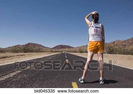 Stock Photography - Mixed Race female runner on road. Fotosearch