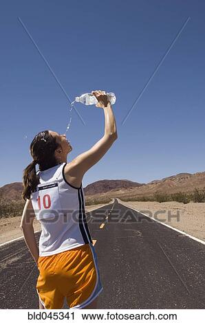 Stock Image - Mixed Race female runner pouring water on face. Fotosearch