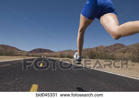 Stock Image - Mixed Race woman running on road. Fotosearch