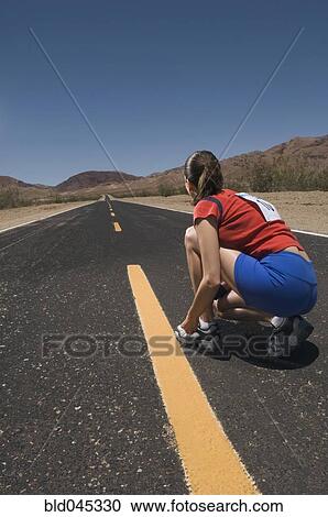 Stock Image - Mixed Race woman tying running shoe. Fotosearch