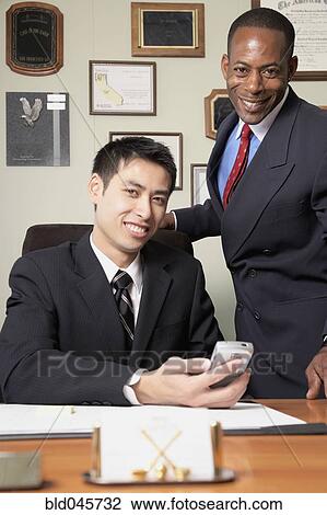 Stock Image - Multi-ethnic businessmen behind desk. Fotosearch