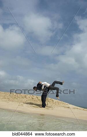 Picture - Multi-ethnic businesspeople tied together at beach. Fotosearch