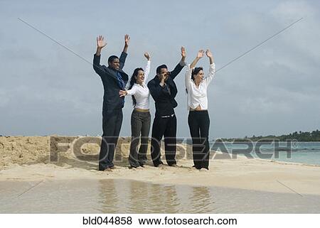 Stock Photo - Multi-ethnic businesspeople waving at beach. Fotosearch