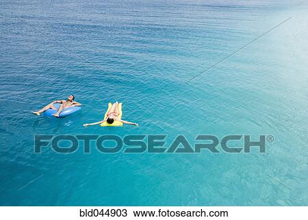 Multi-ethnic couple on floats in water View Large Photo Image Stock Image - Multi-ethnic couple on floats in water. Fotosearch