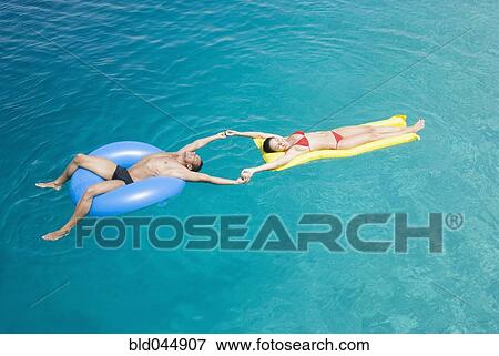 Multi-ethnic couple on floats in water View Large Photo Image Stock Photo - Multi-ethnic couple on floats in water. Fotosearch