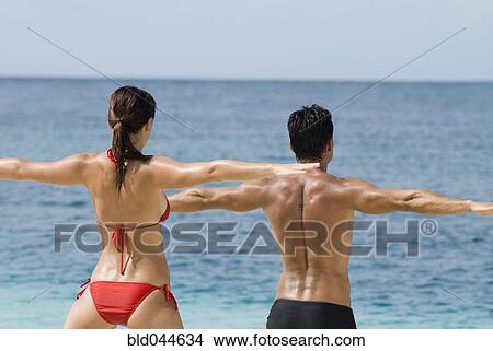 Picture - Multi-ethnic couple practicing yoga at beach. Fotosearch