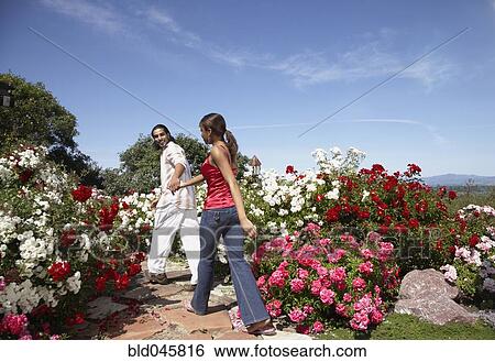 Stock Photograph - Multi-ethnic couple walking through garden. Fotosearch