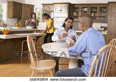 Multi-ethnic couples preparing dinner and playing cards View Large Photo Image Picture - Multi-ethnic couples preparing dinner and playing cards. Fotosearch